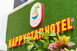 a sign on a green wall with a plant at Happy Star Hotel Nha Trang in Nha Trang