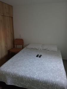 a bedroom with a bed with a white bedspread and a chair at Apartamento en Edificio Puerto paraiso en Bello Antioquia in Bello