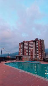 a swimming pool in front of a large building at Apartamento en Edificio Puerto paraiso en Bello Antioquia in Bello