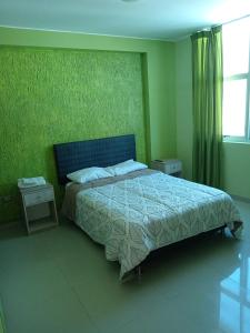 ein Schlafzimmer mit einem Bett und einer grünen Wand in der Unterkunft Gardella House, Casa - Hotel in Ica