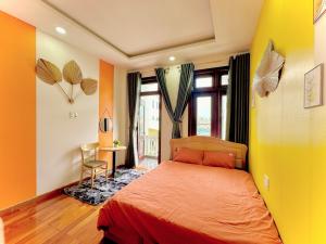 a bedroom with an orange bed and a yellow wall at Mon's House in Da Lat