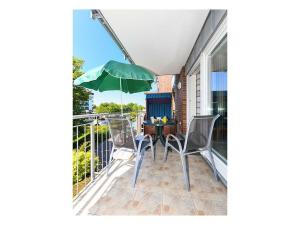 a patio with a table and chairs and a green umbrella at Friesengold Modern retreat in Bensersiel