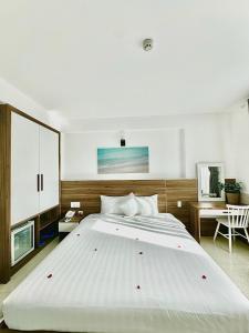 een groot wit bed in een slaapkamer met een bureau bij Tuấn Ninh Hotel I in Con Dao