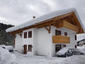 dom z pokrytym śniegiem dachem z samochodami zaparkowanymi na zewnątrz w obiekcie Schachen Modern retreat w Garmisch Partenkirchen