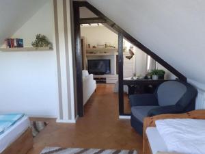 Habitación con escalera, silla azul y TV. en "Lake view" Modern retreat, en Torgelow am See