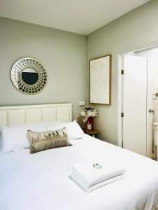 Schlafzimmer mit einem weißen Bett und einem Spiegel an der Wand in der Unterkunft Luna hotel สถานีดอนเมือง in Ban Don Muang