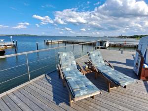 twee ligstoelen op een steiger naast het water bij Houseboat Harmony in Stralsund