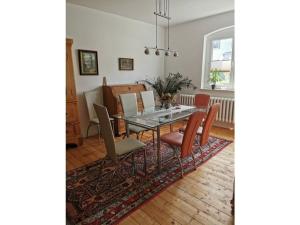 una sala da pranzo con tavolo in vetro e sedie di Haus Waldliebe Modern retreat a Hüttenrode