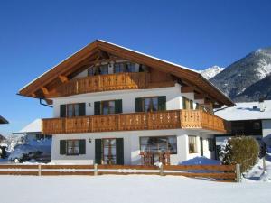 a large house with a wooden balcony in the snow at Holiday apartment "Wetterstein" in Krün