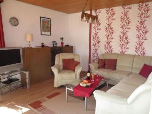 uma sala de estar com um sofá e cadeiras e uma televisão em Kläs Haus Eifelsonne 