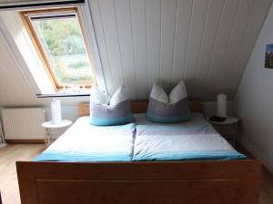 a bed with two pillows on it in a room at Holiday apartment by the forest in Kölpinsee