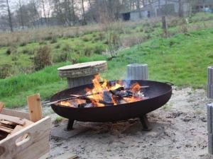 un grand grill avec feu dans un champ dans l'établissement Ferienhof Junge Modern retreat, à Wingst