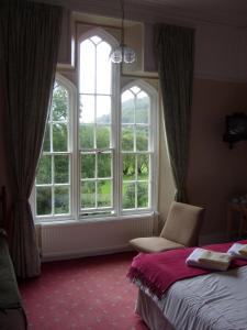 a bedroom with two windows and a bed and a chair at Meadowbank in Ambleside