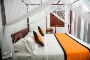 a bedroom with a large bed with orange and white pillows at Villa Ramfort, Galle Fort in Galle