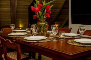 a table with plates and glasses and a vase with red flowers at Villa Ramfort, Galle Fort in Galle