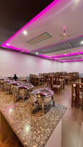 a restaurant with a row of tables and purple lights at Jaisalmer Unique Desert Camp in Sām