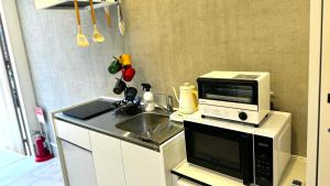 eine Küche mit Mikrowelle und Spüle in der Unterkunft 加美屋リゾート伊勢神宮 おかげテラス in Uji
