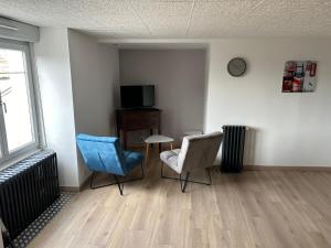 Zimmer mit 2 Stühlen, einem Tisch und einem TV in der Unterkunft Appart in Rougemont