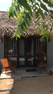 Ranna的住宿－Waves cabana kalametiya，一座带稻草屋顶的建筑,配有长凳和椅子