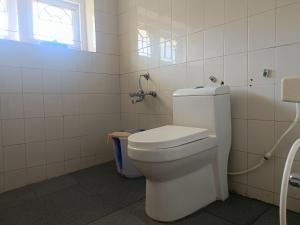 een badkamer met een wit toilet en een raam bij QUEENS COTTAGE - individual cottage in Ooty