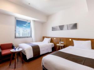 那覇市にあるホテルグレイスリー那覇のベッド2台と窓が備わるホテルルームです。