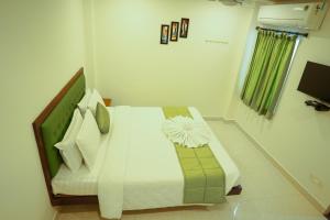 ポンディシェリにあるSAARA INNのベッドルーム1室(白いシーツと枕のベッド1台付)