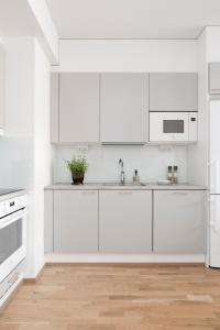 a white kitchen with white appliances and a wooden floor at 2BR design home 400 m from train station Tikkurila in Vantaa