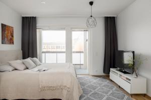 a white bedroom with a bed and a tv at 2BR design home 400 m from train station Tikkurila in Vantaa