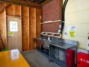 a kitchen with a sink and a brick wall at G-4 Gramping Sauna 白馬森のわさび農園 in Hakuba