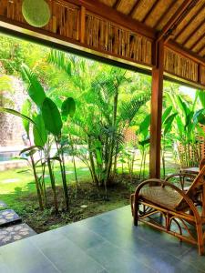 een afgeschermde veranda met een bank en palmbomen bij Pool House Studios in Kuta Lombok