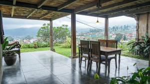 a table and chairs on a porch with a view at Baleluhur Villa Ciwidey in Panundaan
