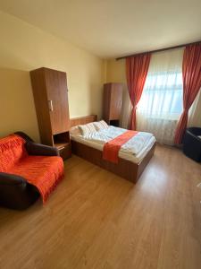 a bedroom with a bed and a chair and a window at Pensiunea Drobeta in Drobeta-Turnu Severin