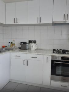 a white kitchen with white cabinets and a stove at Balatonberényi Vendégház in Balatonberény