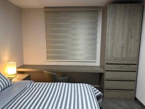 a bedroom with a bed and a window with blinds at PuntaAcero Fundidora y Cintermex in Monterrey