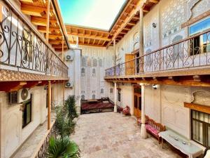 an indoor courtyard with a balcony and a bench at Porso Boutique Hotel in Bukhara