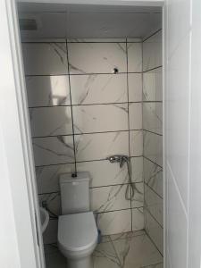 a bathroom with a toilet and a tiled wall at ULASOTEL22 in Edirne