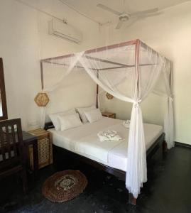 a bedroom with a bed with a canopy at Agra Arugambay in Arugam Bay
