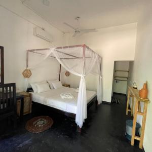 1 dormitorio con 1 cama con dosel en Agra Arugambay en Arugam Bay