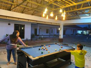 Eine Frau und ein Junge spielen Billard. in der Unterkunft Ocean Villa, Radiant Teluk Sari in Kampung Mawar
