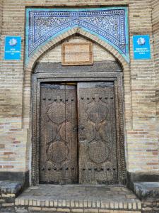 una gran puerta de madera en un edificio de ladrillo en Orient Star Khiva Hotel- Madrasah Muhammad Aminkhan 1855, en Khiva