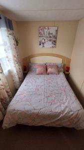 a bedroom with a large bed with a pink comforter at SKYLA VISTA Clacton-on-Sea in Clacton-on-Sea