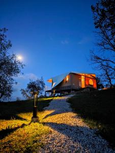 a house sitting on top of a hill at night at Glamping Stregaia in Massa Marittima
