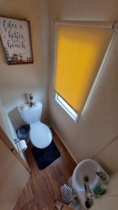 Elle comprend une petite salle de bains pourvue de toilettes et d'une fenêtre. dans l'établissement SKYLA VISTA Clacton-on-Sea, à Clacton-on-Sea