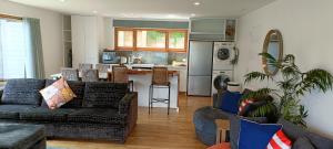 a living room with a couch and a kitchen at New luxury waterfront accommodation in Dunedin