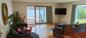 New luxury waterfront accommodation في دنيدن: غرفة معيشة بها أريكة وكراسي وتلفزيون