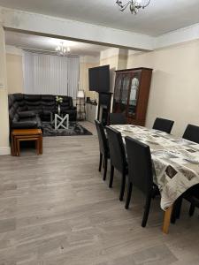 uma sala de jantar com uma mesa e cadeiras e um sofá em ELSARO guest house em Slough