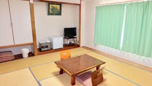 a living room with a table and a television at パームビーチリゾートホテル in Oshima