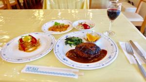 una tavola con piatti di cibo e un bicchiere di vino di パームビーチリゾートホテル a Oshima