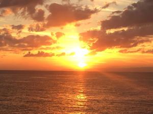 una puesta de sol sobre el océano con la puesta de sol en パームビーチリゾートホテル en Oshima