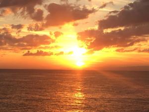 a sunset over the ocean with the sun setting at パームビーチリゾートホテル in Oshima